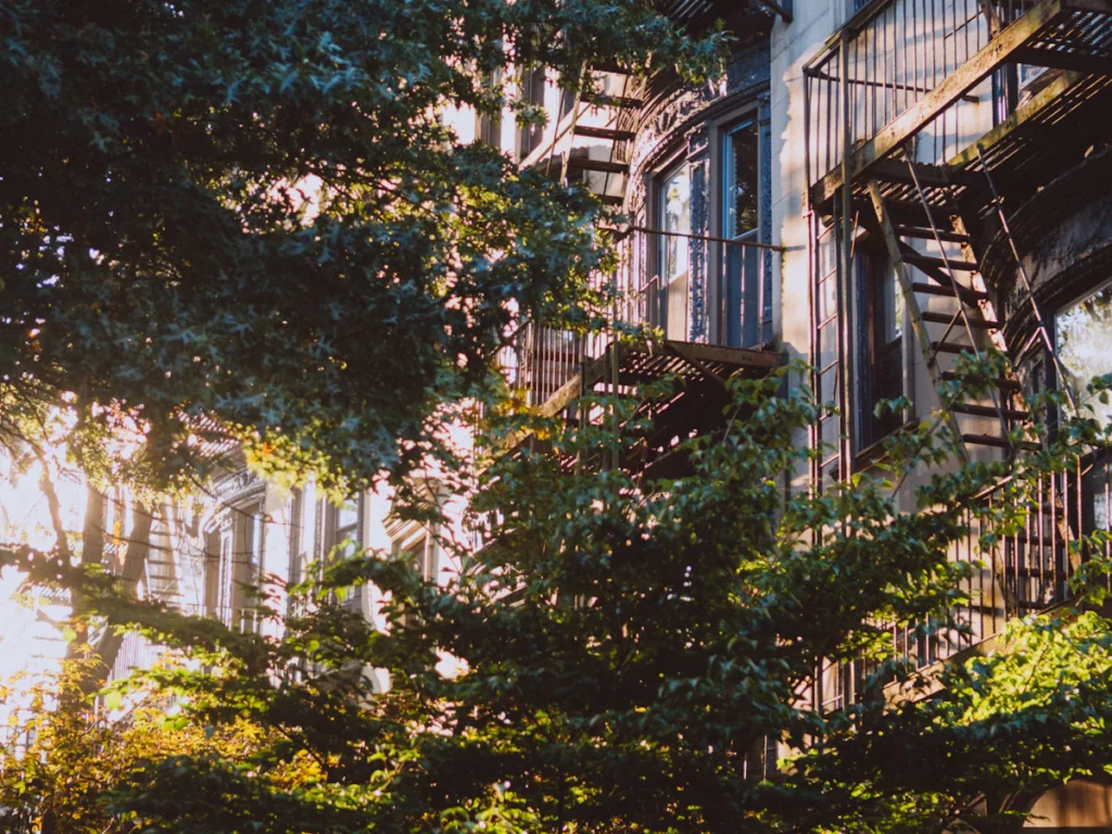Apartment building fire escapes behind street trees, the kind of fire escapes cited by fire inspectors for violations in Westchester