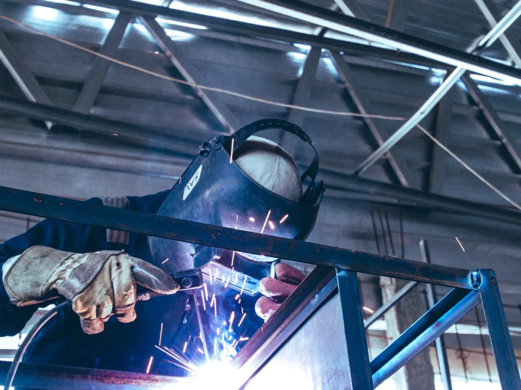 Welder in a protective helmet welding a steel frame, the structural welding used for fire escape repair in Westchester NY