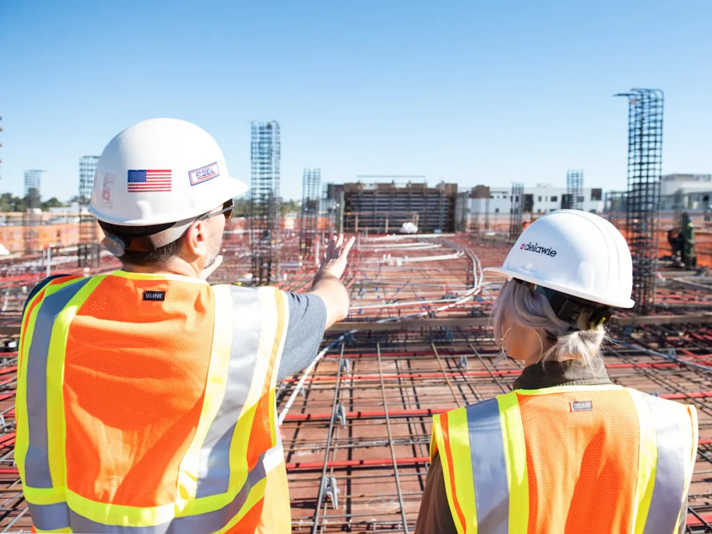 Two inspectors in hard hats and safety vests reviewing a site, the kind of re-inspection that closes a fire escape violation in Westchester