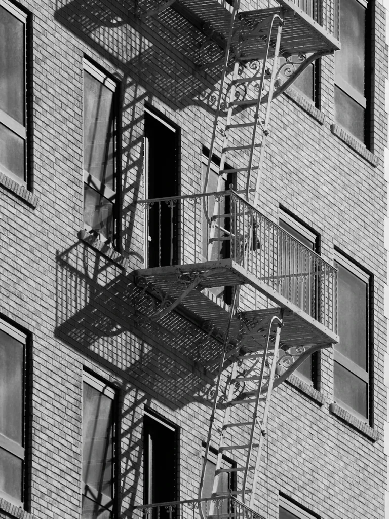 Fire escape platform and railing anchored to a brick wall, where wall anchor repair keeps Westchester fire escapes attached to the building