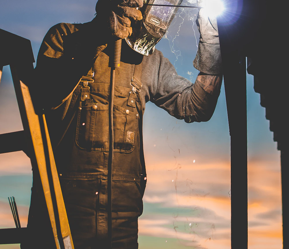 Welder in a protective hood and work jacket welding exterior steel, licensed and insured fire escape crew in Westchester